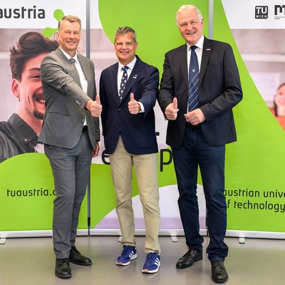 drei Männer stehend, lächelnd und Daumen nach oben