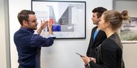 Ein Mann erklärt zwei Studierenden technische Aspekte im Brückenbau