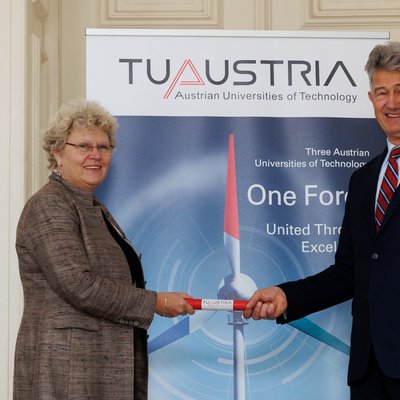 Eine Frau überreicht ein Staffelholz an an einen Mann