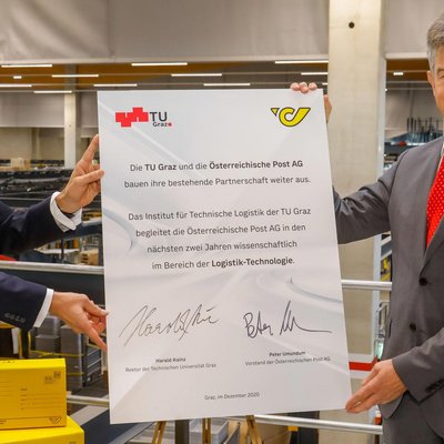 Zwei Männer halten ein gemeinsam signiertes Plakat in die Höhe