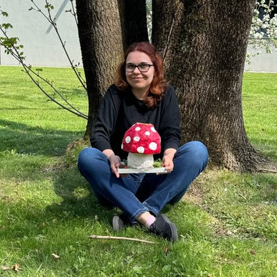 Jessica Michalke posiert unter einem Baum mit einem selbstgebasteltem Pilz aus Pappe