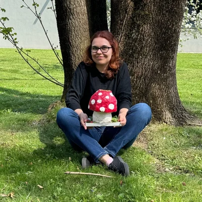 Jessica Michalke posiert unter einem Baum mit einem selbstgebasteltem Pilz aus Pappe
