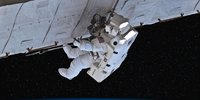 Astronaut im weißen Raumanzug bei Arbeiten im All.