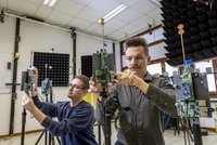 Zwei Männer schrauben mit Antennen und Platinen ausgestattete Geräte zusammen.