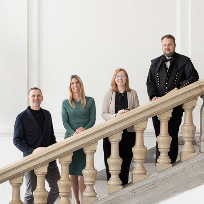 Der Universitätsprofessor steht zusammen mit den drei Habilitationsschreibern auf der Universitätstreppe. 