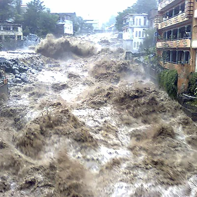 Ein schlammiger Fluss führt braunes Wasser und zerstört die angrenzenden Häuser.