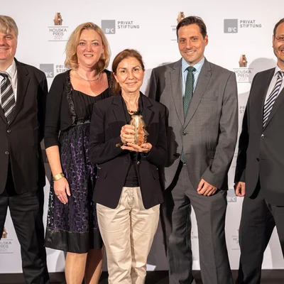 Golta Khatibi hält den Houska-Award in der Hand. Im Hintergrund ihr 4-köpfiges Team. 