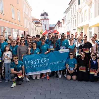 Teilnehmer*innen des Teams der Montanuniversität Leoben beim LE-Laufevent in der Leobener Innenstadt vor dem Start, mit Erasmus+-Banner und Startnummern.
