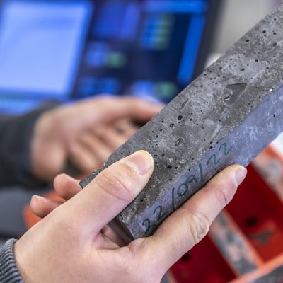 Detailaufnahme von Händen mit einem Quader aus betonähnlicher Substanz.
