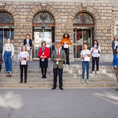 Gruppe aus Schülerinnen und Erwachsenen auf einem Stiegenaufgang vor Gebäudeeingang
