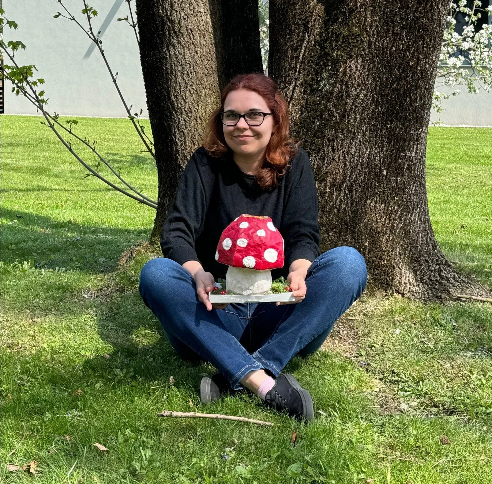 Jessica Michalke posiert unter einem Baum mit einem selbstgebastaltem Pilz aus Pappe