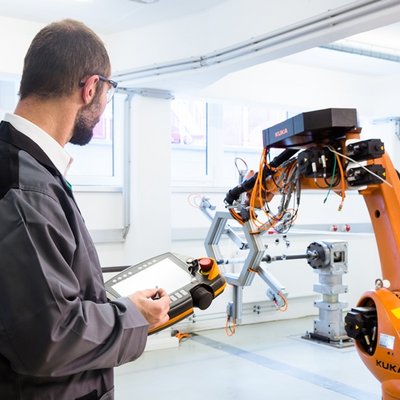 Mann in Werkhalle an Maschine: Faserverbund-Bauteile für die Luft- und Raumfahrt werden zu einem großen Teil Stück für Stück mit einem Wickelroboter hergestellt.