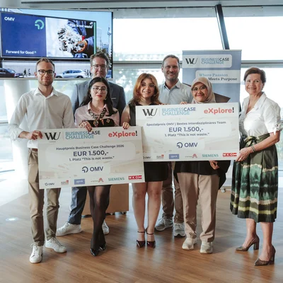 Gruppe von sieben Personen bei einer Preisverleihung an der WU; zwei Teilnehmende halten große Sieger-Schecks der Business Case Challenge mit Partner-Logos wie OMV.