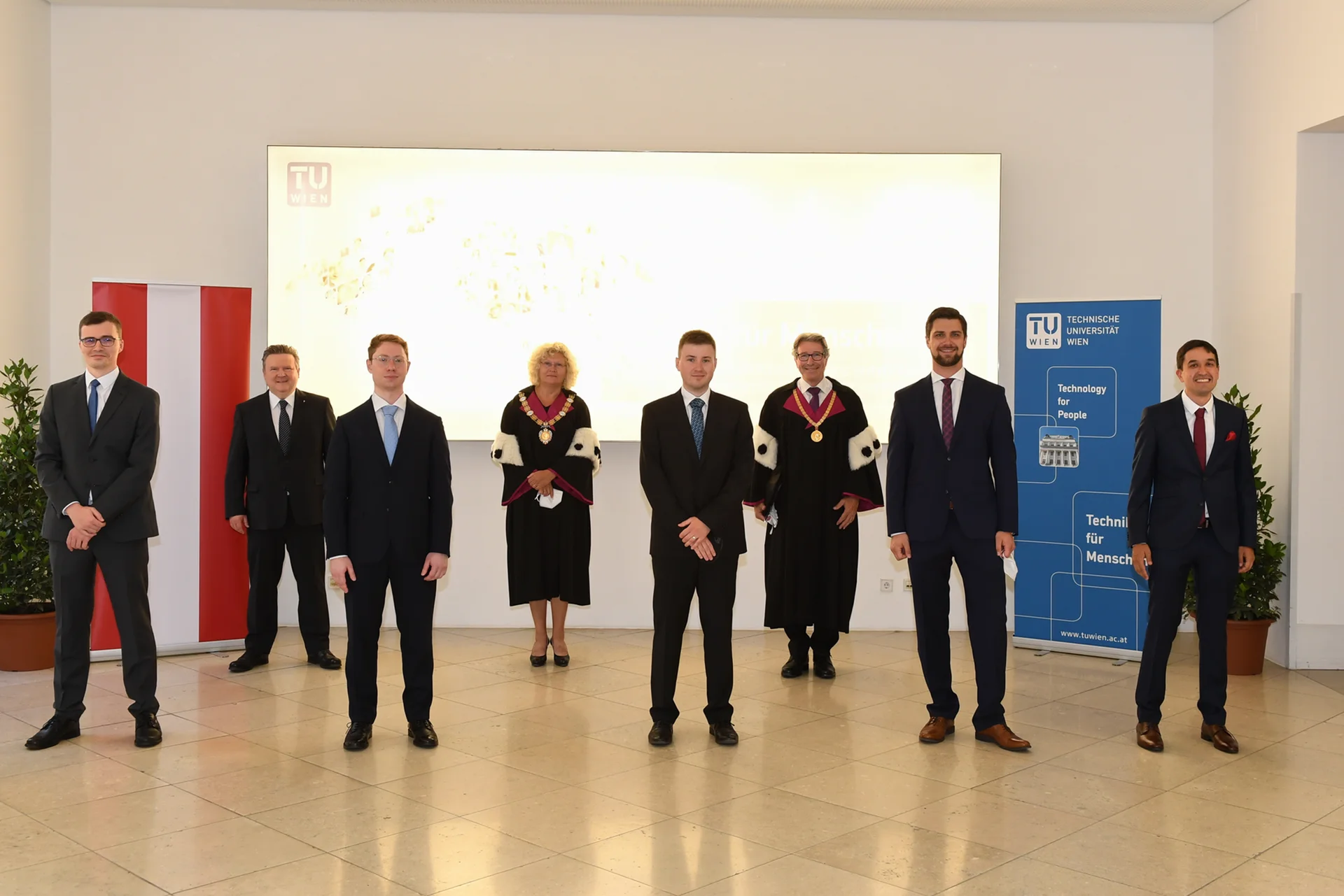 Gruppenfoto der Sub auspiciis Absolvent_innen mit Rektorin Seidler, Vizerektor Matyas und Bürgermeister Ludwig vor TU Wien Logo