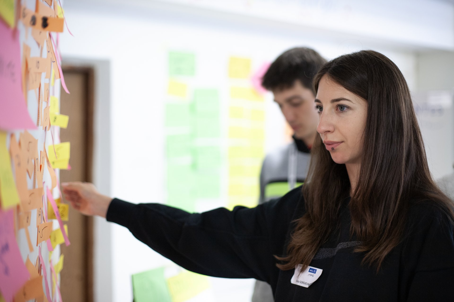 Studierenden-Teams arbeiteten an Lösungen Studentin steht an Flipchart.
