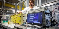Mann mit Brille vor einem Versuchsaufbau mit Laptop