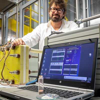 Mann mit Brille vor einem Versuchsaufbau mit Laptop