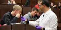 Lehrender mit Studierenden im Hörsaal